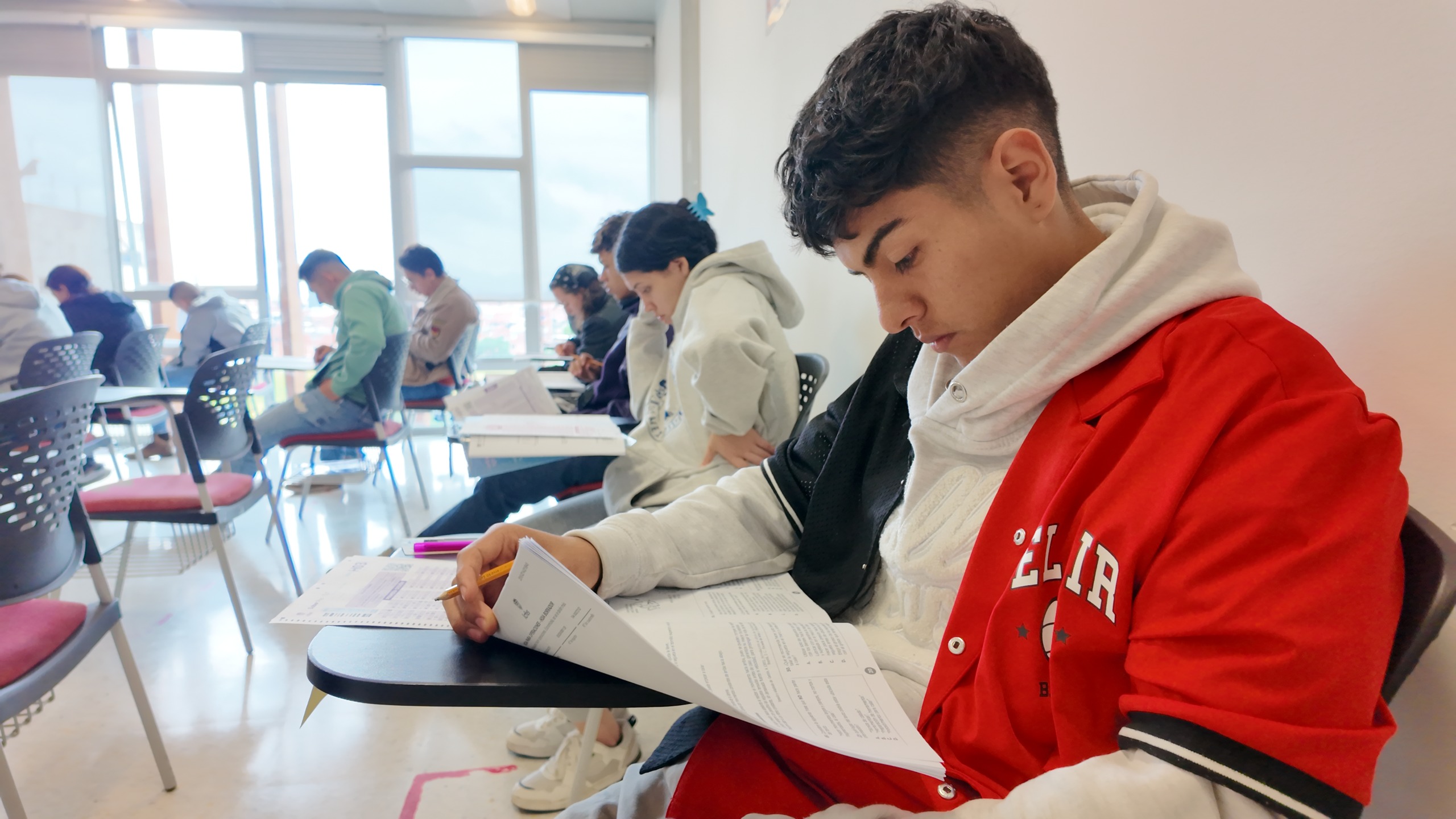 Joven en salón de clase resolviendo prueba